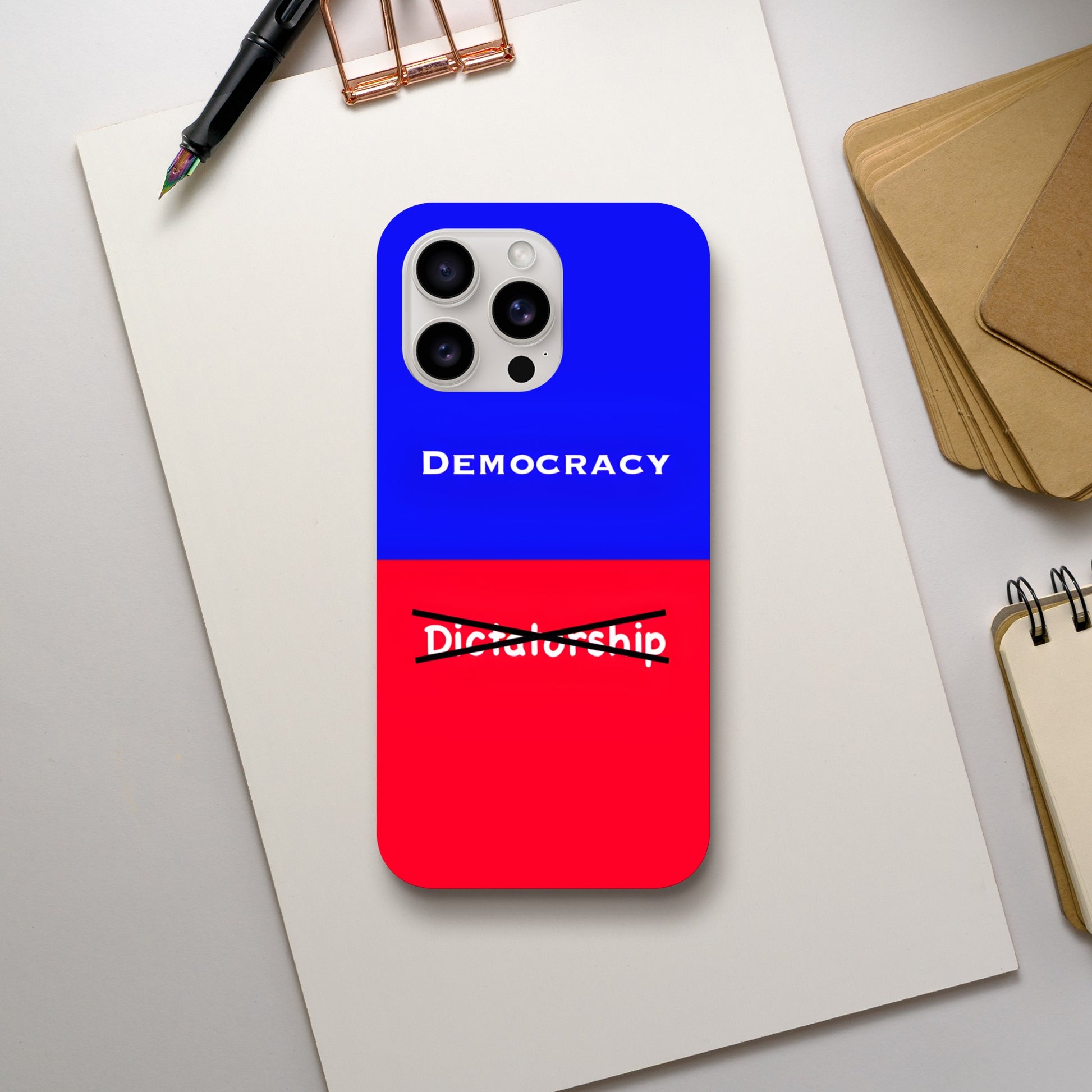 An Apple iPhone 15 Pro Max Phone Case with the following design on it: A visual comparison of two posters, the one on top features the term "Democracy”; written in white, against a royal blue background, and the one of the bottom features the term “Dictatorship" which is also written in white but is crossed out by two black lines, highlighting the preference for Democracy. 